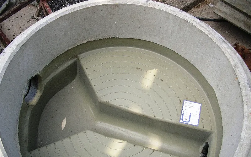 Grease interceptor cleaning: the inside of an in-ground grease interceptor tank and its baffle