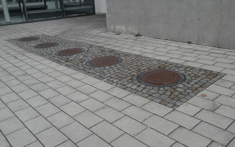 Grease interceptor pumping: a row of in-ground grease interceptor lids set in paving